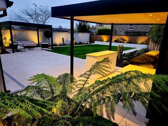 Landscaped garden with lit pergola and evening seating area