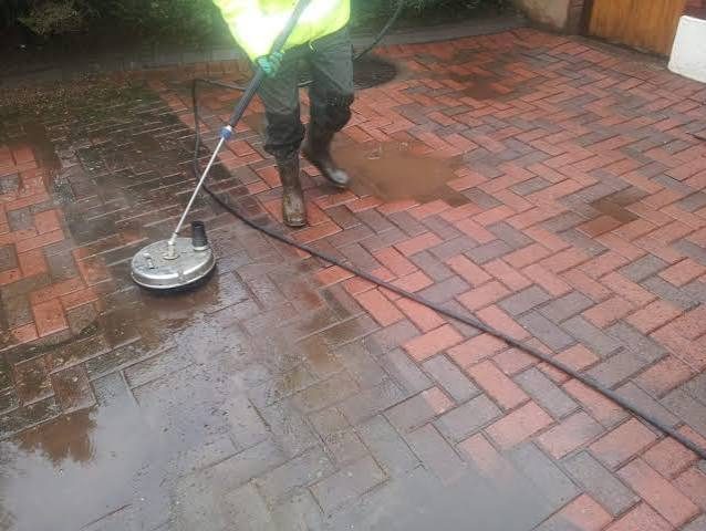 Pressure washing a red brick patio, removing moss and staining
