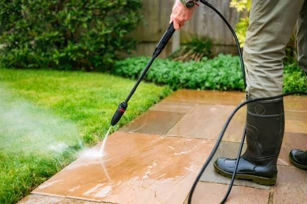 Pressure washing a garden patio next to a lawn